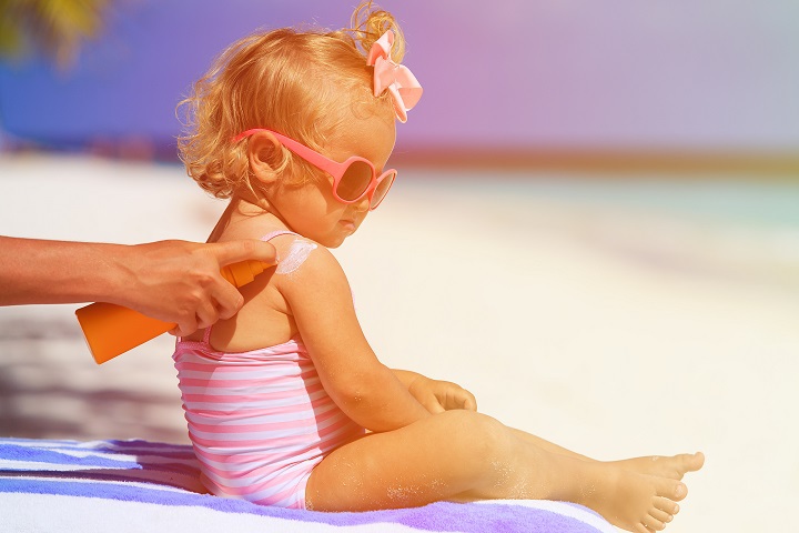 mother applying sunblock cream on daughter shoulder