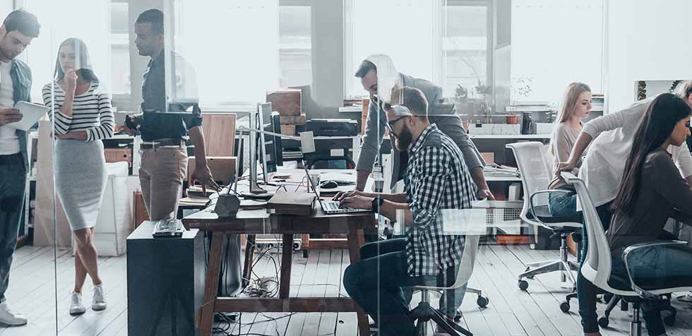 Office environment with people working and collaborating at desks with computers