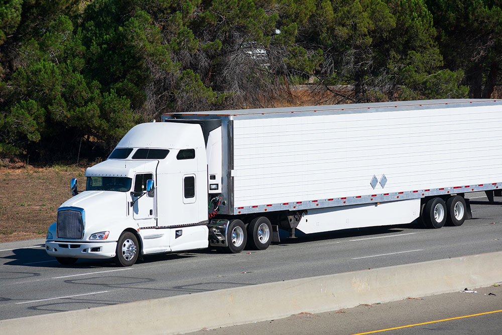 White semi-truck with a large trailer driving on a highway